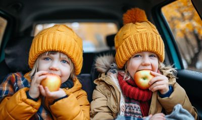 Kinder essen Apfel auf Autorückbank