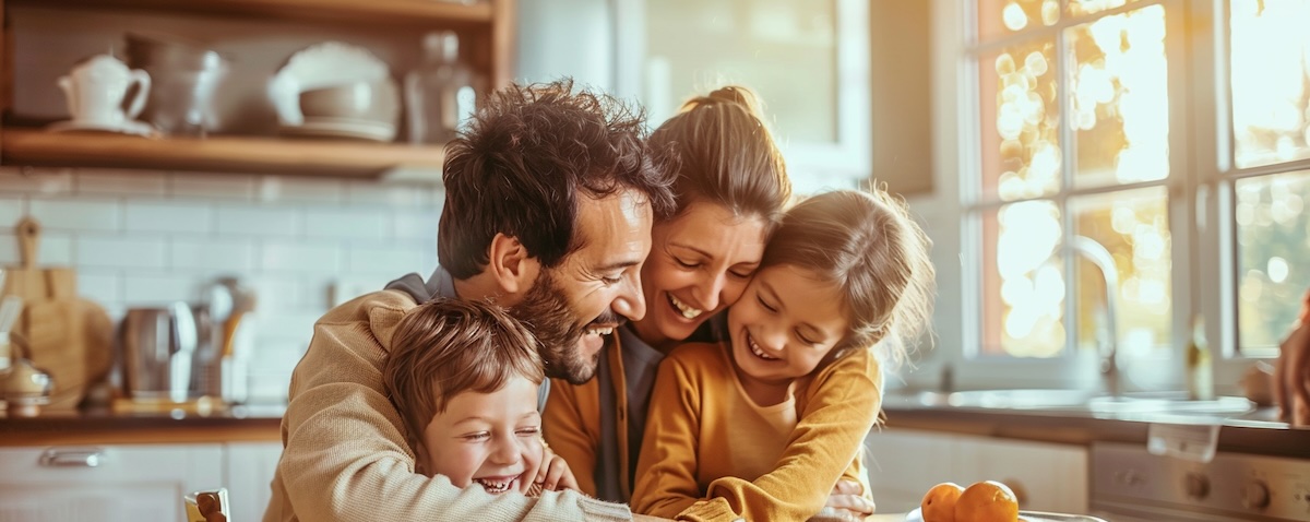 Familie mit zwei Kindern sitzt gemeinsam am Frühstückstisch in hellem Zuhause